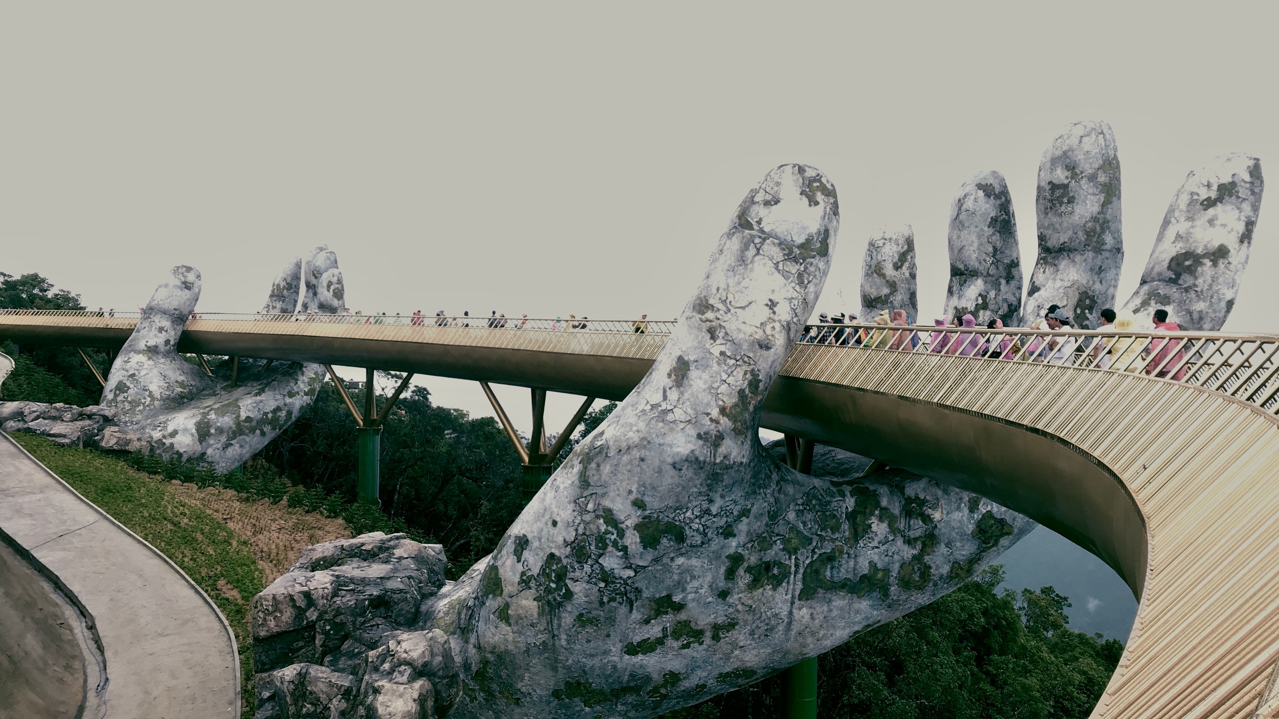 Golden bridge supported by giant stone hands representing pathway and guidance
